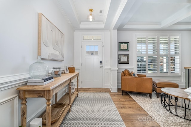 entrance foyer with a raised ceiling, ornamental molding, and light wood-type flooring