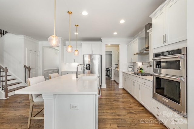 kitchen with dark wood-type flooring, decorative light fixtures, white cabinets, a breakfast bar area, and an island with sink