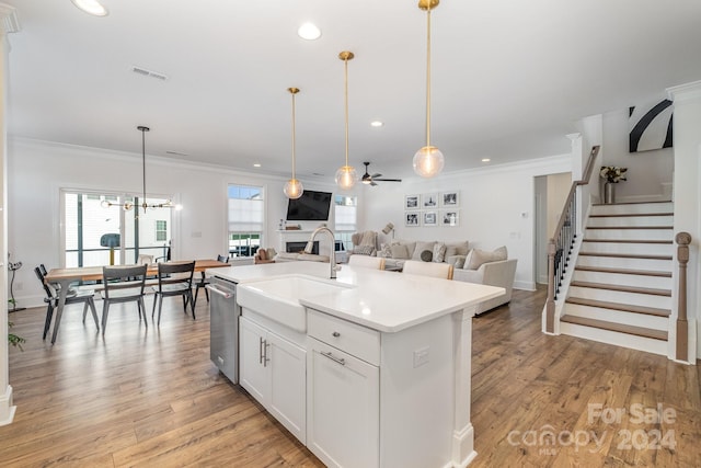 kitchen with crown molding, white cabinetry, an island with sink, and light hardwood / wood-style flooring