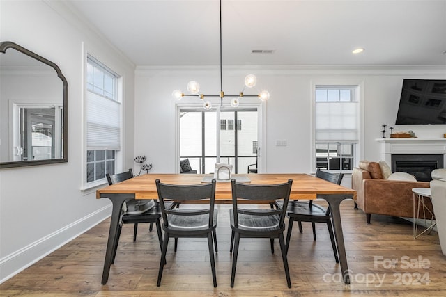 dining space featuring hardwood / wood-style flooring, a notable chandelier, and ornamental molding