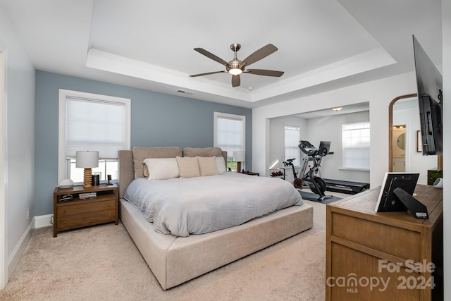 bedroom with light colored carpet, crown molding, ceiling fan, and a tray ceiling