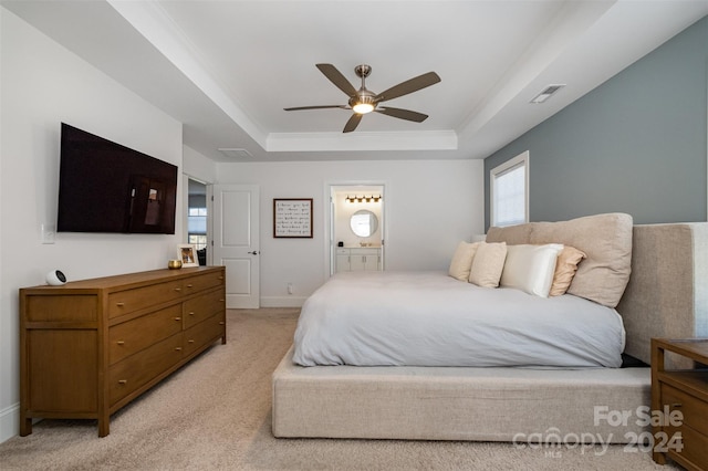 carpeted bedroom with ensuite bathroom, a raised ceiling, and ceiling fan