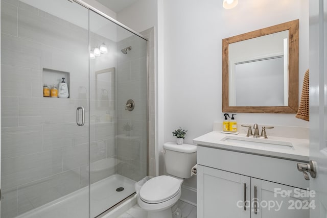 bathroom featuring vanity, toilet, and a shower with shower door