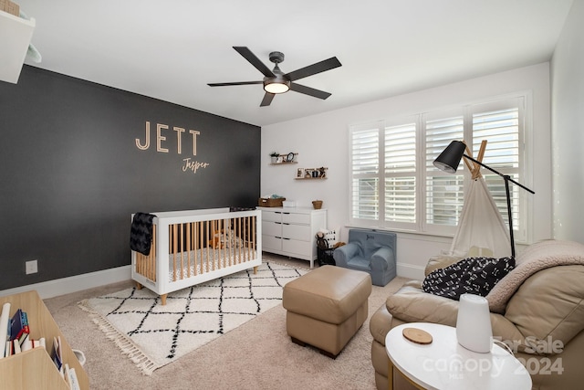 carpeted bedroom featuring a crib and ceiling fan