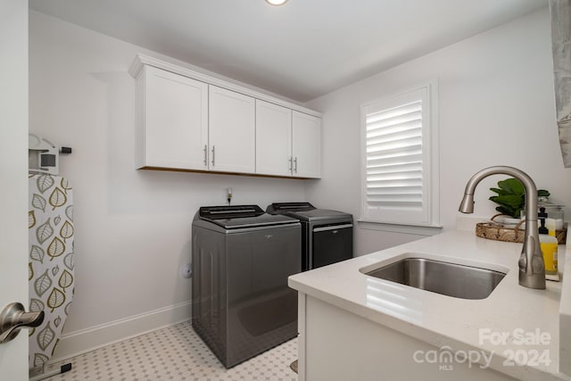 washroom featuring washing machine and dryer, sink, and cabinets