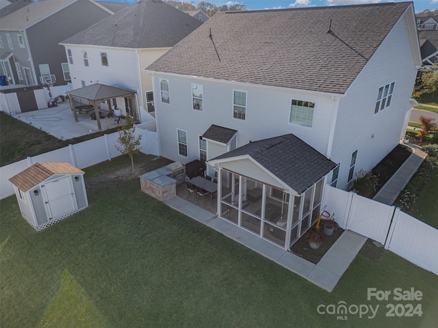 back of property with a yard, a storage unit, and a sunroom