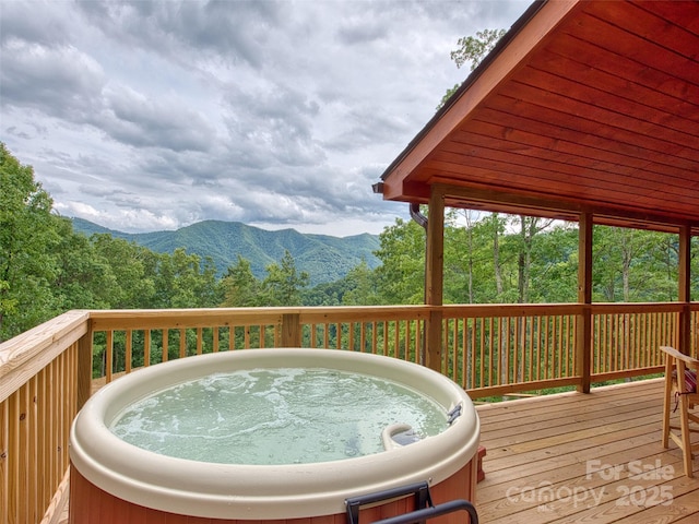 wooden deck with a hot tub and a mountain view