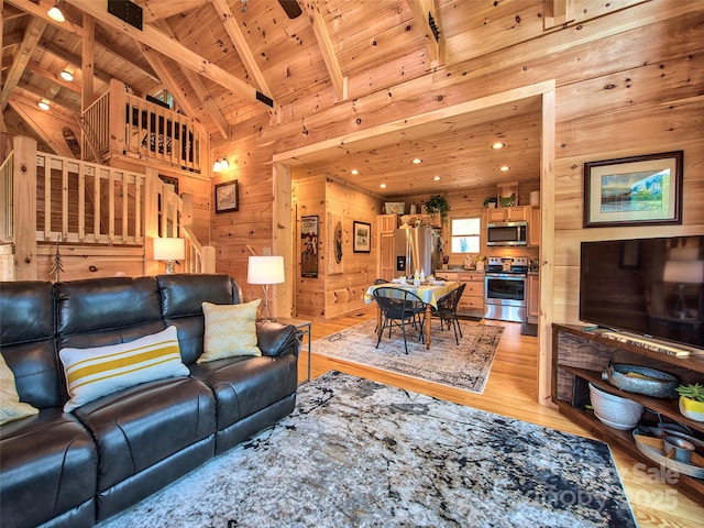 living room with wood ceiling, high vaulted ceiling, light wood-type flooring, wooden walls, and beamed ceiling