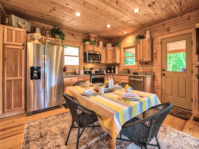 dining room with light hardwood / wood-style flooring, wooden ceiling, and wood walls