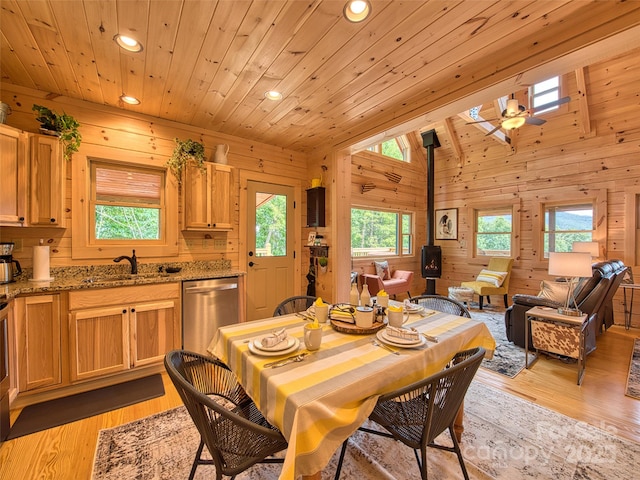 dining space featuring plenty of natural light, a wood stove, sink, and wooden walls