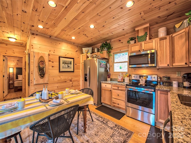 kitchen with wooden walls, stainless steel appliances, light stone countertops, wooden ceiling, and light hardwood / wood-style flooring