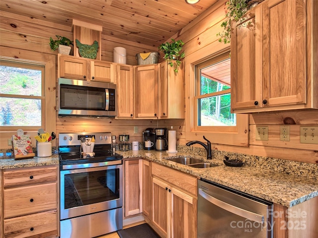 kitchen featuring wooden walls, sink, wood ceiling, stainless steel appliances, and light stone countertops