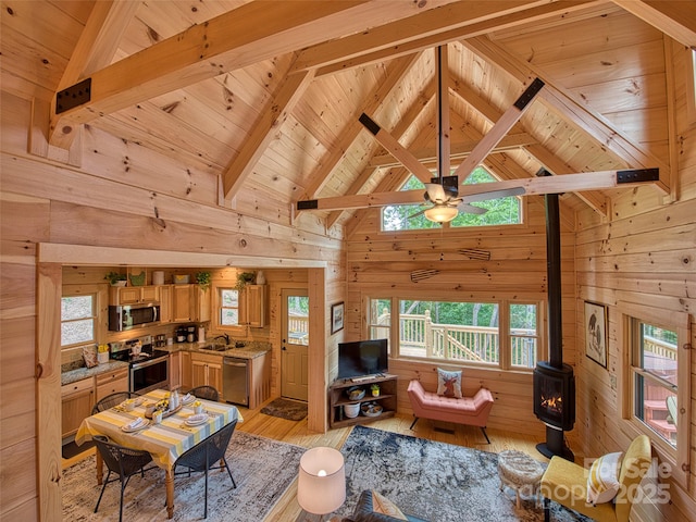 living room featuring wood walls, beamed ceiling, a wood stove, light hardwood / wood-style floors, and wood ceiling