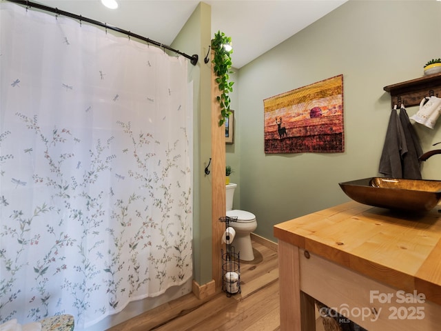 bathroom with sink, hardwood / wood-style flooring, toilet, and walk in shower