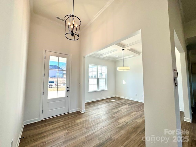 foyer entrance featuring hardwood / wood-style floors, an inviting chandelier, beam ceiling, crown molding, and coffered ceiling