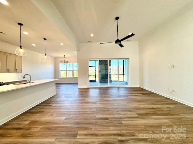 unfurnished living room with sink, ceiling fan with notable chandelier, and hardwood / wood-style flooring