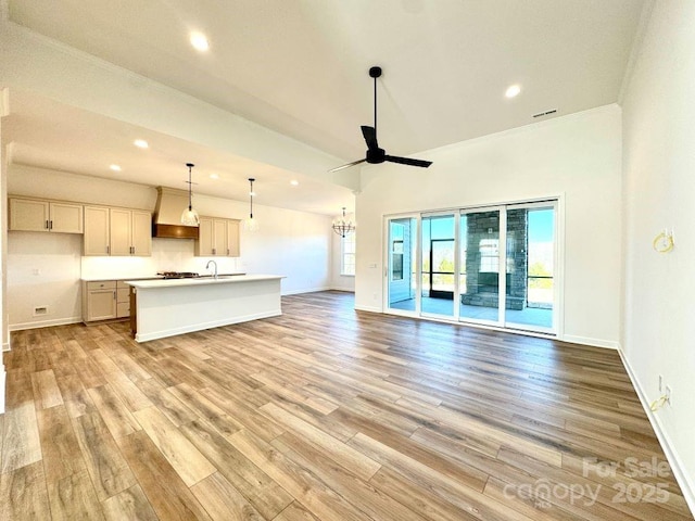 unfurnished living room featuring sink, ceiling fan, crown molding, and light hardwood / wood-style flooring