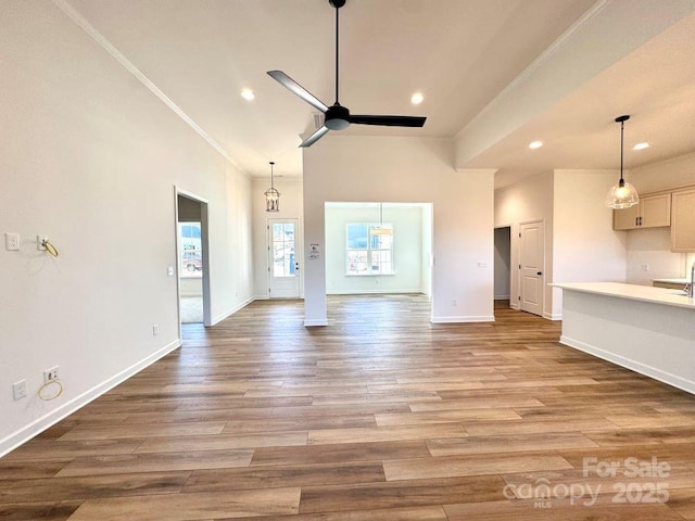 unfurnished living room with a high ceiling, ornamental molding, light hardwood / wood-style floors, and ceiling fan