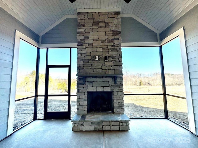 unfurnished living room featuring a healthy amount of sunlight, concrete floors, and an outdoor stone fireplace