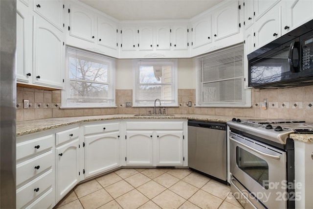 kitchen with light stone counters, light tile patterned floors, appliances with stainless steel finishes, white cabinetry, and a sink