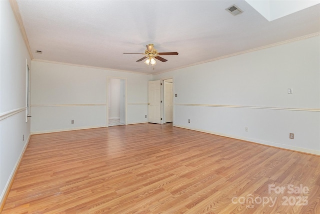 spare room with light wood-style floors, visible vents, and crown molding