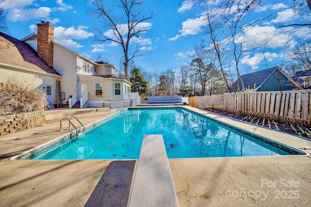 view of swimming pool with a diving board, a patio, fence, and a fenced in pool