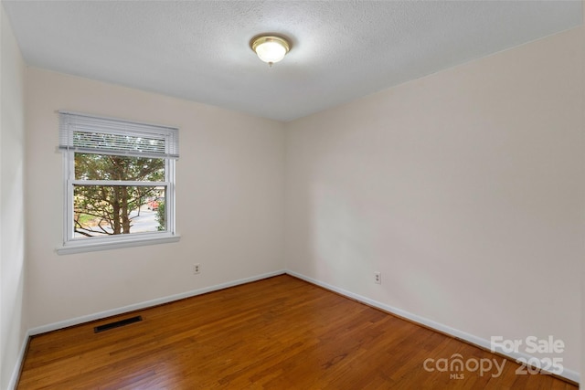 empty room with hardwood / wood-style flooring and a textured ceiling