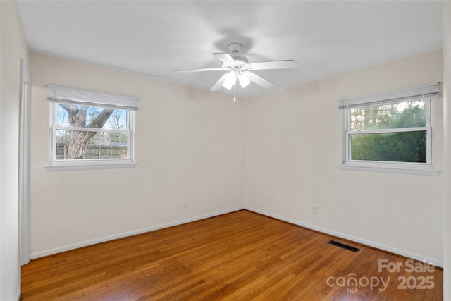 unfurnished room with hardwood / wood-style floors, a wealth of natural light, and ceiling fan