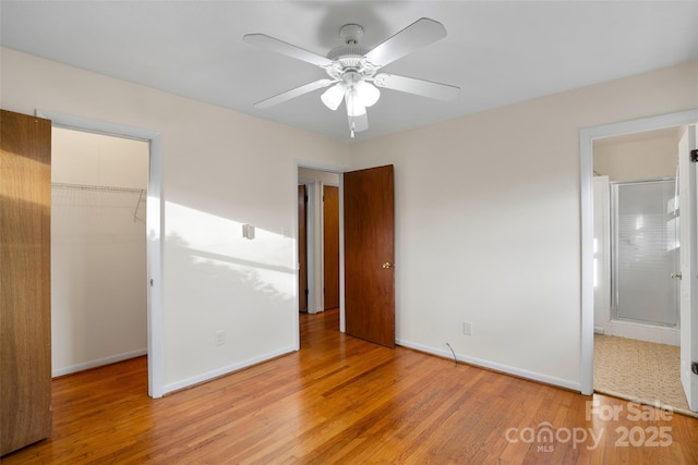 unfurnished bedroom featuring ensuite bathroom, ceiling fan, light hardwood / wood-style flooring, a spacious closet, and a closet