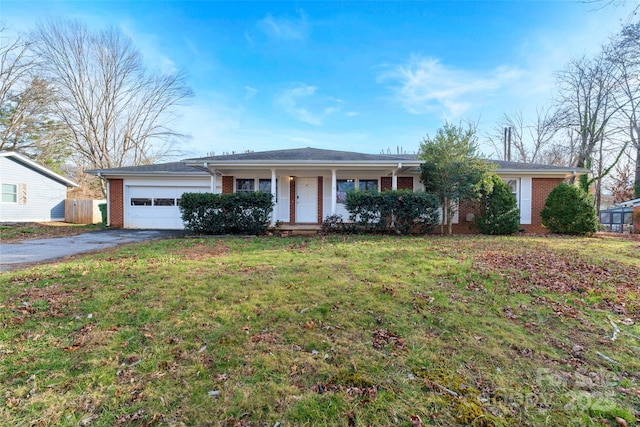 ranch-style house featuring covered porch, a front yard, and a garage