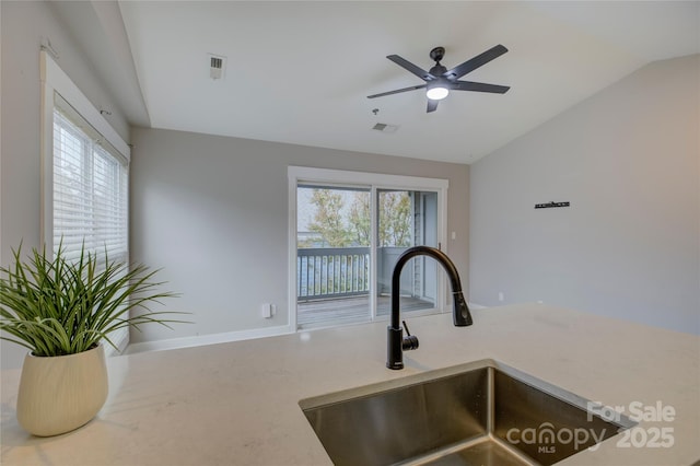 kitchen featuring plenty of natural light, visible vents, vaulted ceiling, and a sink