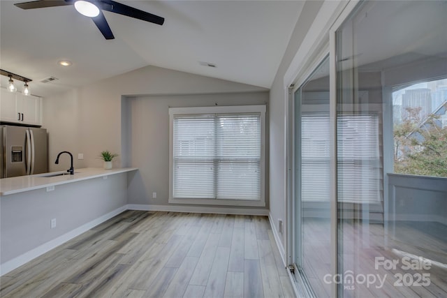 kitchen featuring light wood-style floors, white cabinets, vaulted ceiling, a sink, and stainless steel fridge with ice dispenser