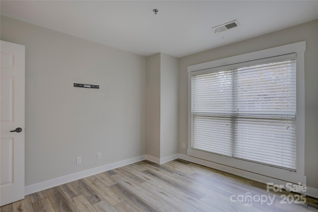 spare room with visible vents, light wood-style flooring, and baseboards