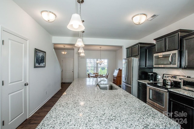 kitchen with light stone countertops, sink, hanging light fixtures, dark hardwood / wood-style flooring, and appliances with stainless steel finishes