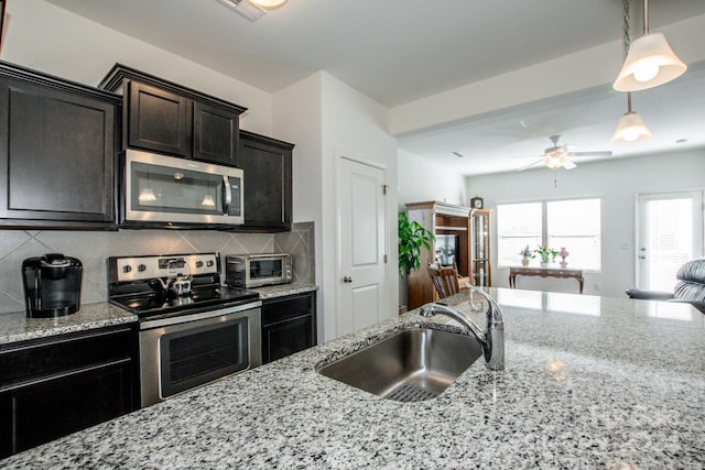 kitchen with tasteful backsplash, stainless steel appliances, ceiling fan, sink, and hanging light fixtures