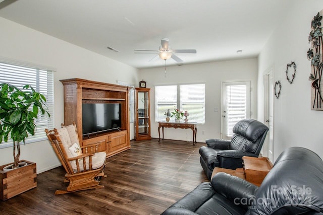 living room with a wealth of natural light, dark wood-type flooring, and ceiling fan