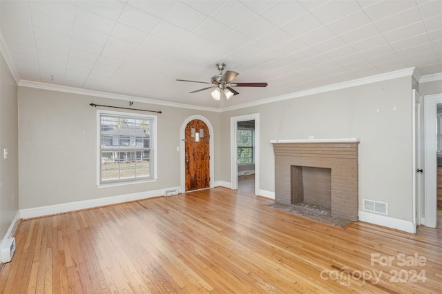 unfurnished living room featuring wood-type flooring, a brick fireplace, ceiling fan, and crown molding