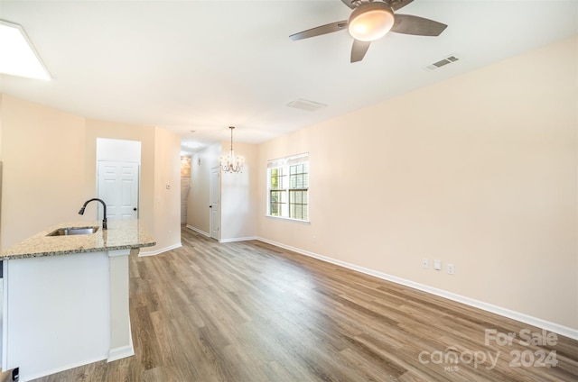 kitchen with light stone countertops, sink, hanging light fixtures, and hardwood / wood-style flooring