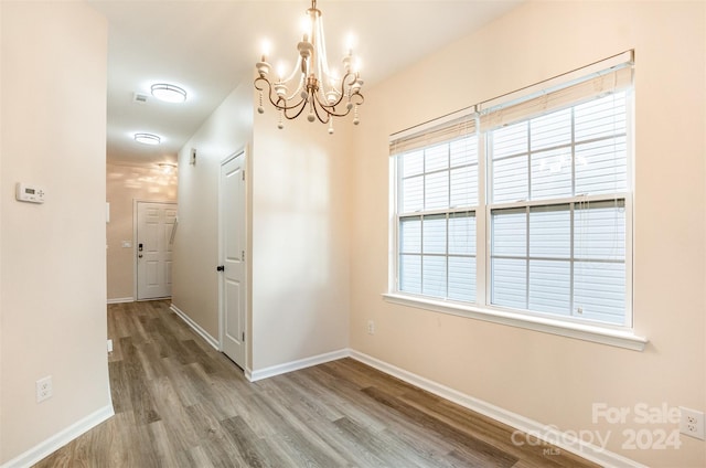 unfurnished dining area with hardwood / wood-style flooring and a notable chandelier