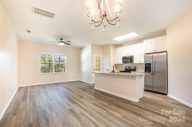 kitchen featuring a kitchen island with sink, white cabinets, hardwood / wood-style flooring, light stone countertops, and appliances with stainless steel finishes