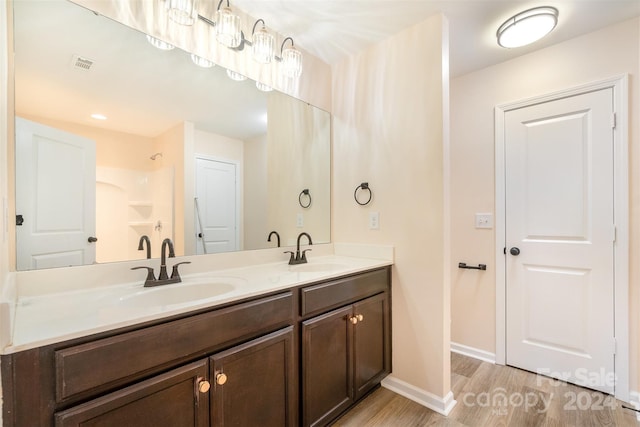 bathroom with hardwood / wood-style floors, vanity, and a shower