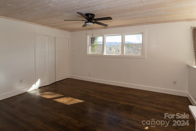 unfurnished bedroom featuring a closet, ceiling fan, dark wood-type flooring, and wood ceiling