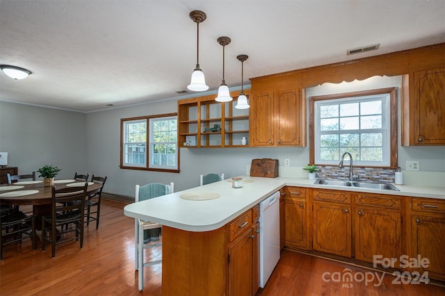 kitchen featuring pendant lighting, plenty of natural light, wood-type flooring, and kitchen peninsula