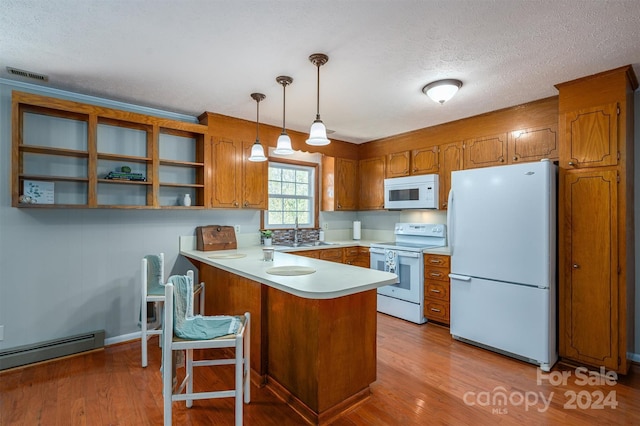 kitchen with sink, kitchen peninsula, pendant lighting, white appliances, and light hardwood / wood-style floors