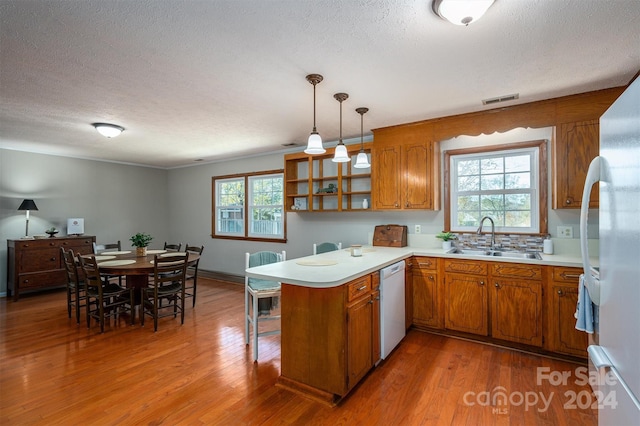 kitchen with kitchen peninsula, white appliances, a wealth of natural light, and sink