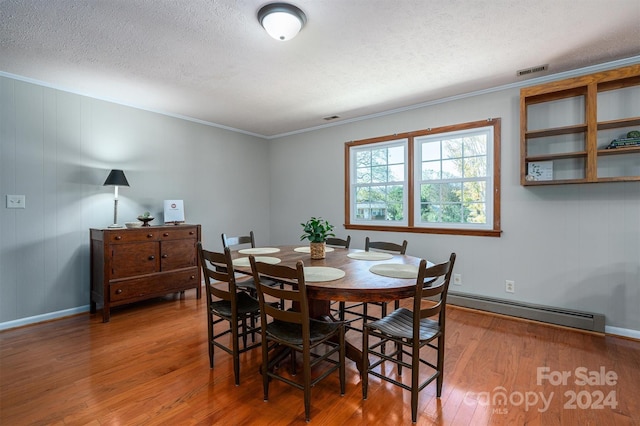 dining space featuring baseboard heating, ornamental molding, a textured ceiling, and hardwood / wood-style flooring