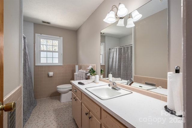 bathroom featuring vanity, toilet, tile walls, and an inviting chandelier