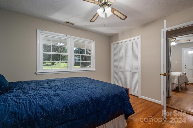 bedroom featuring ceiling fan, wood-type flooring, a textured ceiling, and a closet