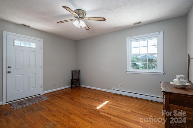 foyer entrance featuring baseboard heating, ceiling fan, a textured ceiling, and light wood-type flooring