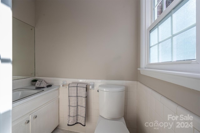 bathroom featuring toilet, plenty of natural light, tile walls, and sink